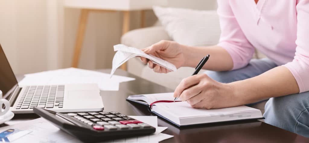 lady with bills noting her purchases at home